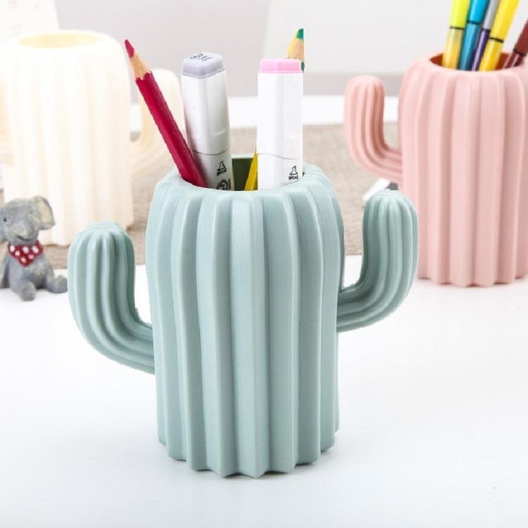 Cactus-shaped pen holder with stationery items on a white surface
